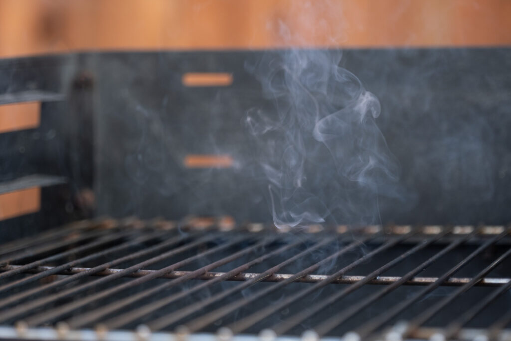 Photograph of smoke emerging from a barbecue.