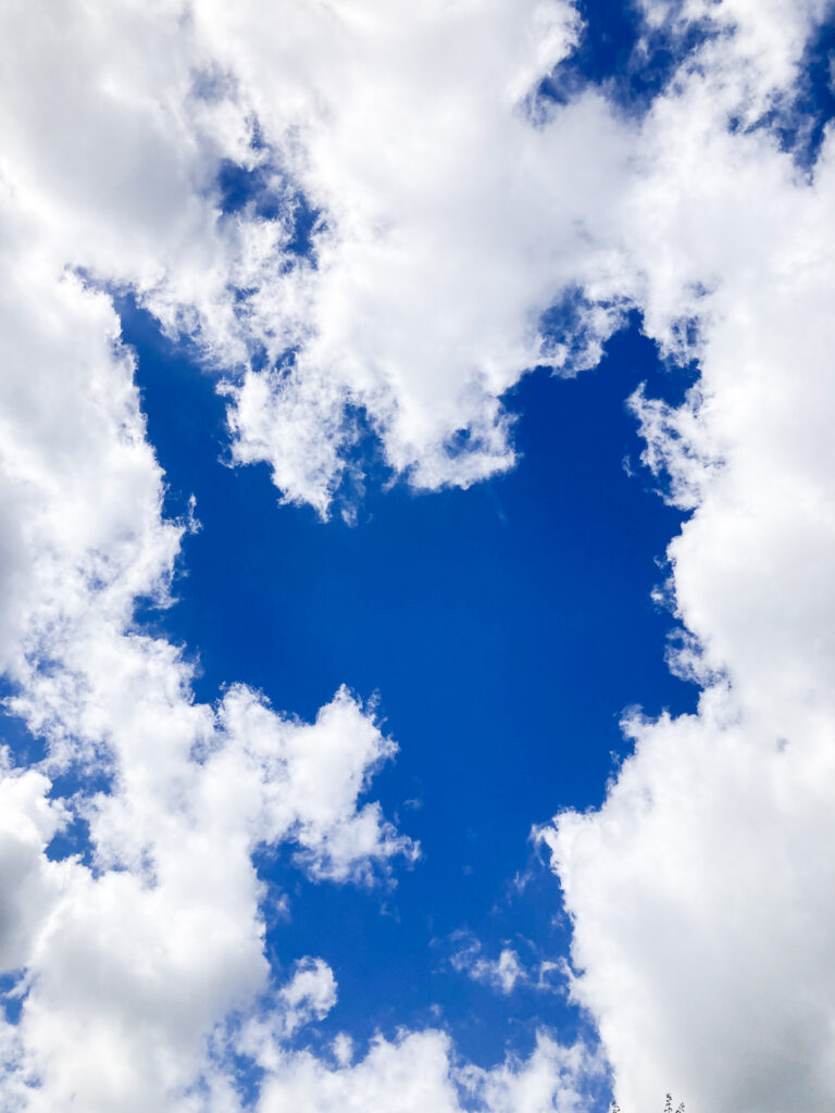 Photograph of a deep blue sky with clouds around the edges.