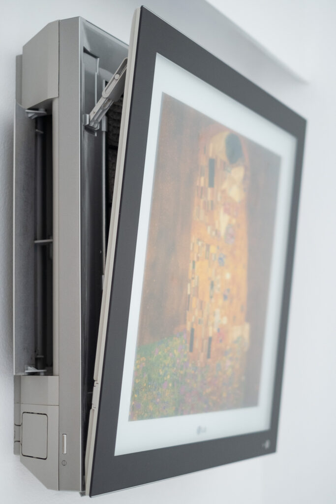 Photograph of an airconditioning unit that has a framed picture of Klimt's Kiss on the front, to disguise it.