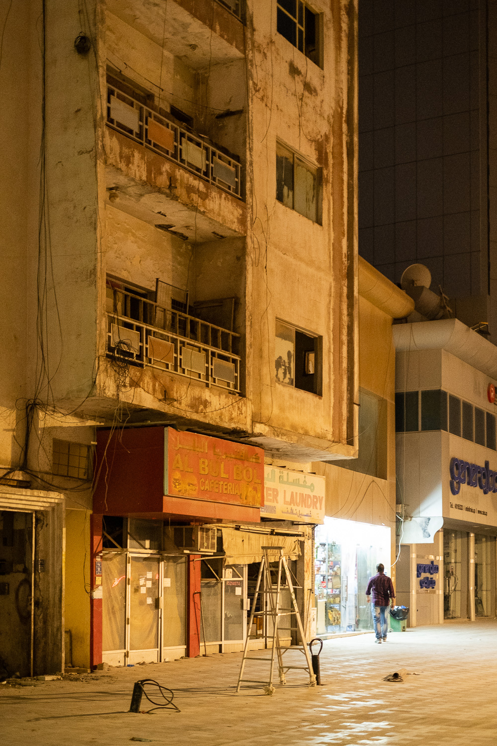 A photograph of a street scene in Doha, Qatar, showing an older, rundown building with a ladder in the foreground. Doha tore down and rebuilt most buildings in preparation for the World Cup 2022.