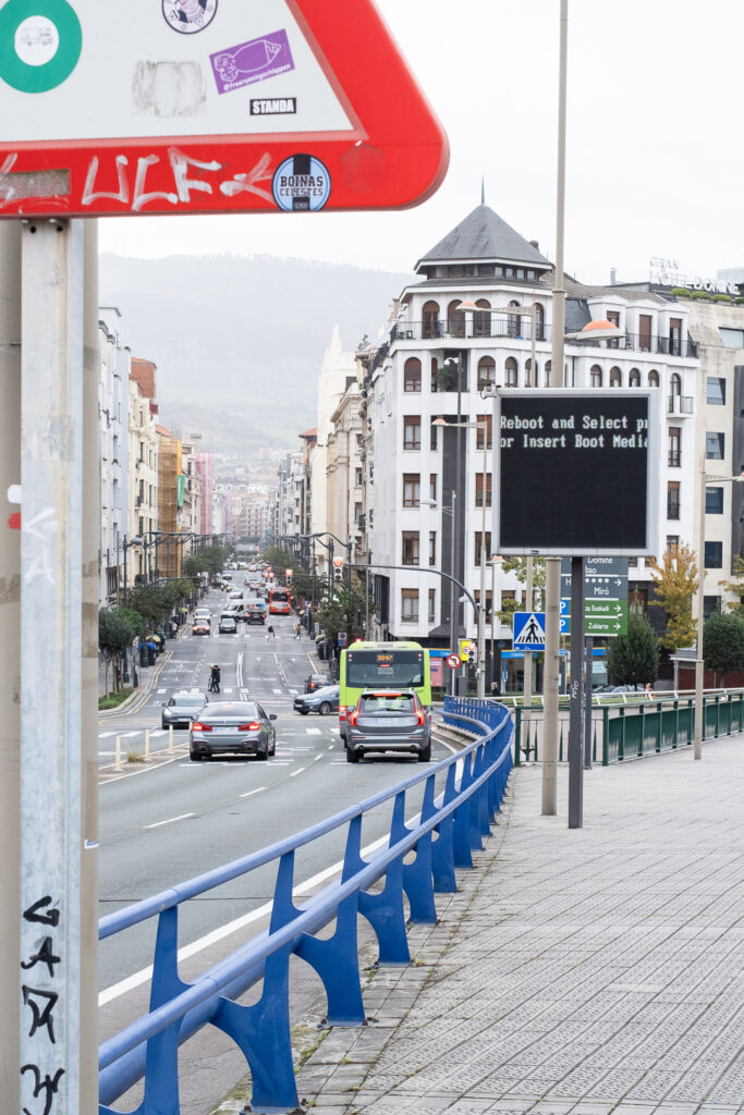 Photograph looking down Salbeko Zubia road, Bilbao, Basque Country. A sign to the right says 'Reboot and select... Insert Boot Media'.