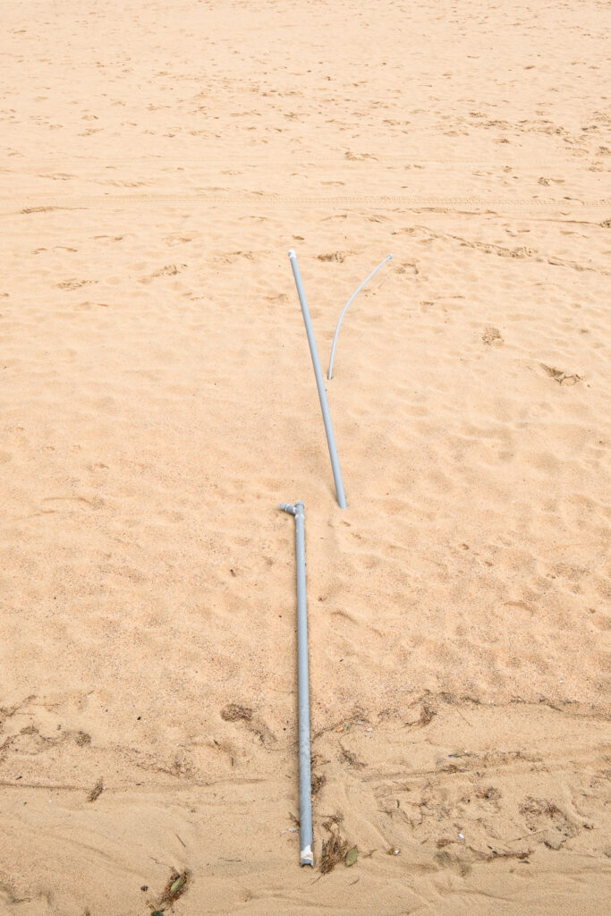 Grey pipes on Ondarreta Beach, Donostia San Sebastian, Basque Country, with footprints and markings around them.