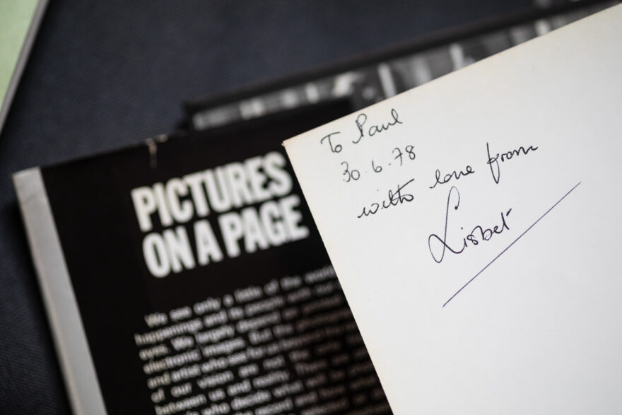 Photograph of a handwritten message on a page in a book, which says 'To Paul, 30.6.78, with love from Lisbet', behind to the left and out of focus is more of the book, with the title 'PICTURES ON A PAGE' just visible.