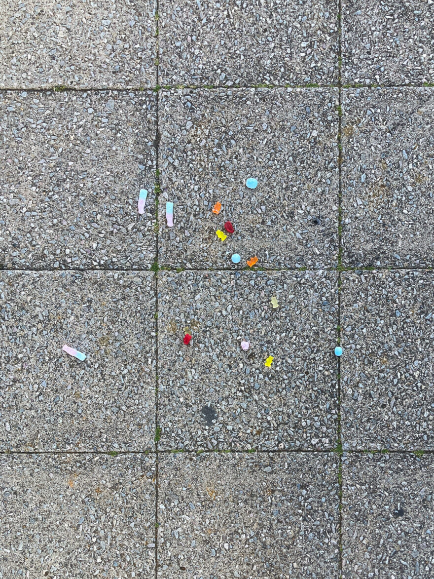 Photograph looking down at paving slabs with colourful pick 'n' mix spilt on them.