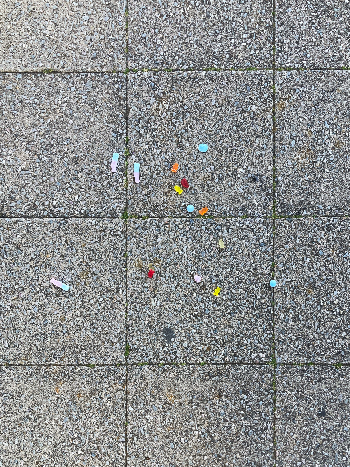 Photograph looking down at paving slabs with colourful pick 'n' mix spilt on them.