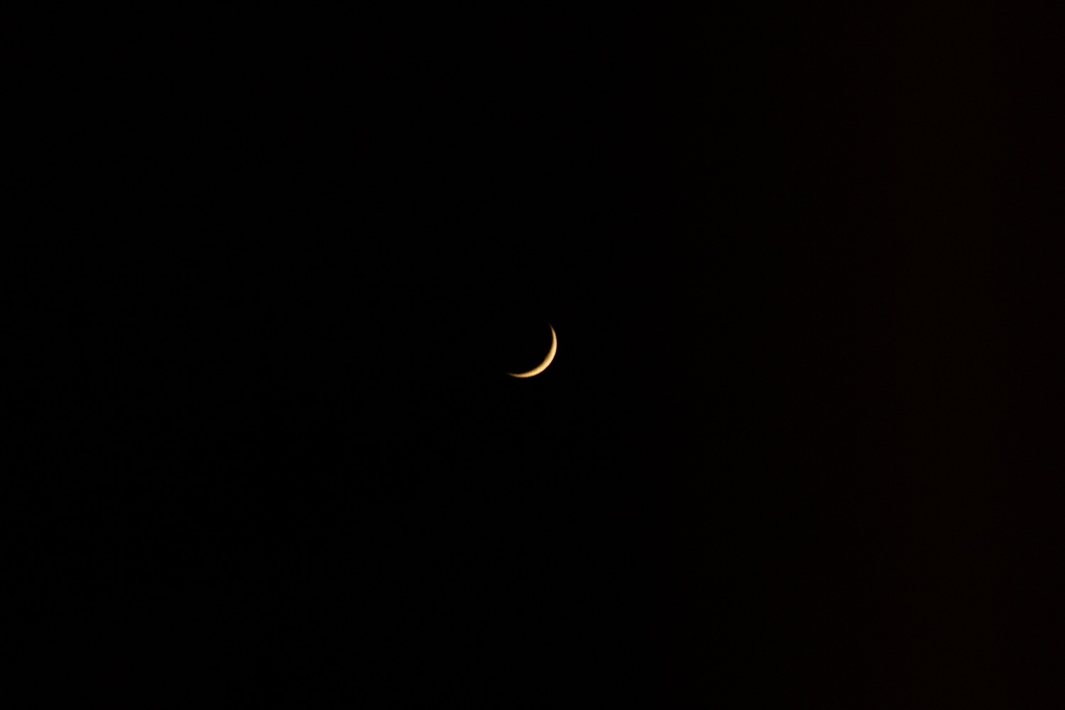 Colchester, January 2025. Photograph of a the moon in a black sky, with only a tiny golden part visible.